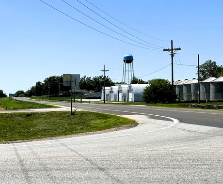 A road going by a town with a water tower and buildings in the background.