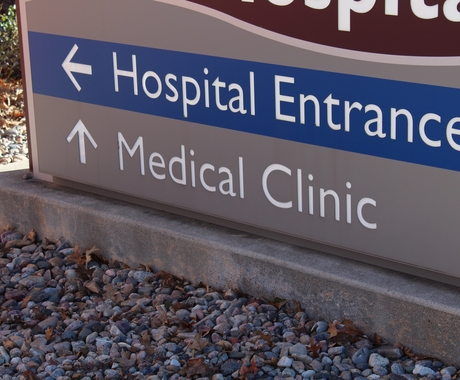 Gray sign with Hospital Entrance in white on a blue background and Medical Clinic in white text on gray background.