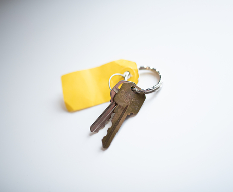 Set of goldish-brown keys on a keyring with a yellow tag on a white background