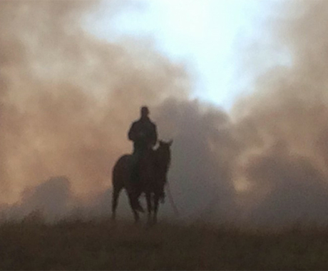 Man on horse with smoke behind him