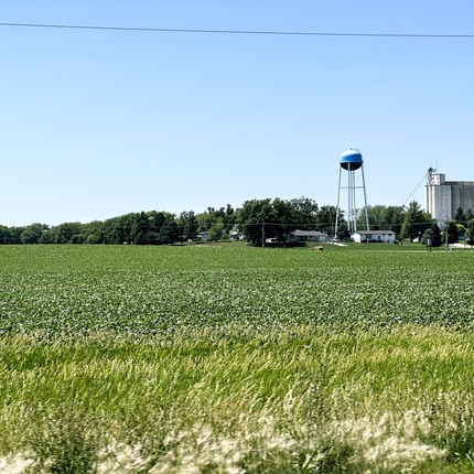 Rural landscape with water tower, homes, businesses and grain bin in the background.