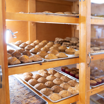 Baked goods, including muffins and cookies, in a display case with a glass front