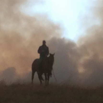 Man on horse with smoke behind him