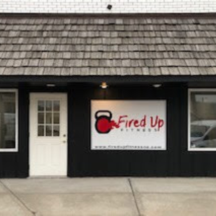 Front of building with black walls, white door, and sign that says "Fired Up Fitness"