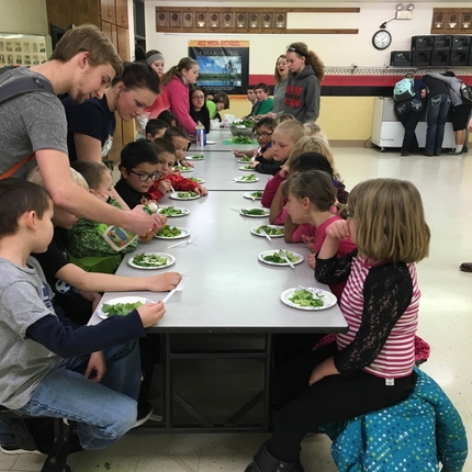 Children sitting at lunch table eating salad