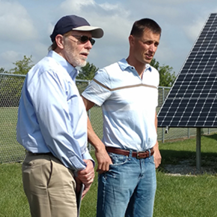Three men in front of solar panel