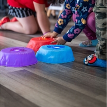 Children bend down to play with toys on the floor. 