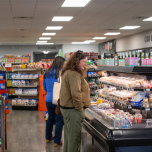 Woman looks through options for on-the-go meals at a small grocery store.