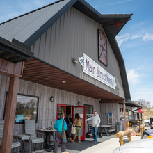 Large barn-like structure with a man holding open the door for people entering.