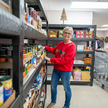 White female stocks shelves at a food pantry.