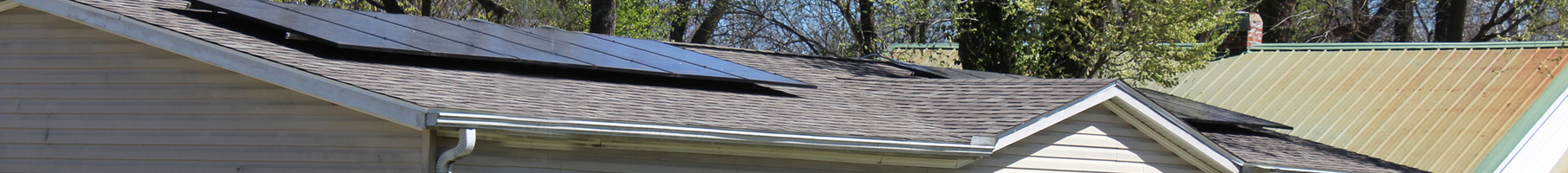 Casa de un piso, color blanquecino, con dos paneles solares separados en el techo.