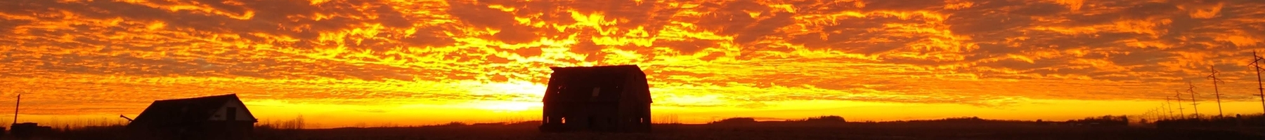Barn on horizon with orange sunset