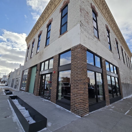 Two story building taken from the corner. Light bricks are on the second story and red bricks are on the first story. Single windows line the second story and double windows line the first.