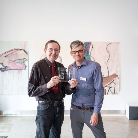 Two men standing and holding an award