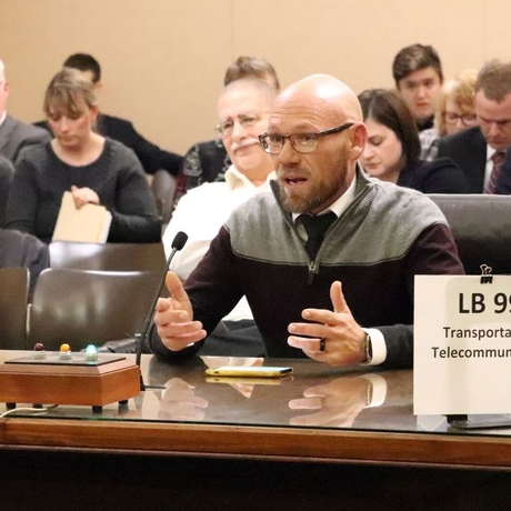 A man sitting at a table speaking into a small mic.