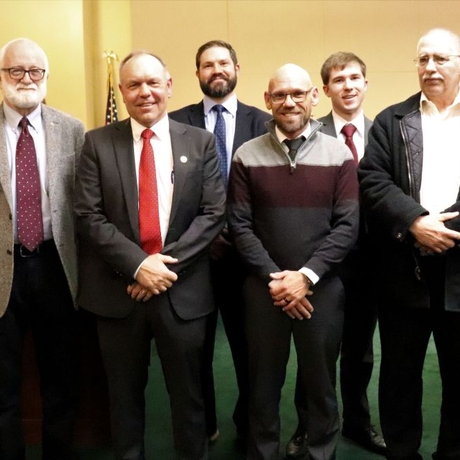 An image of six men in suits standing in a business room.