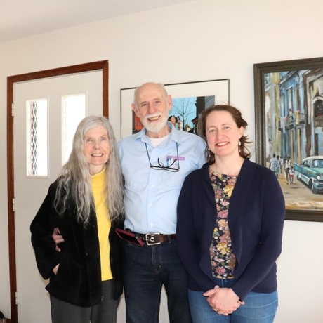 Photo of three people standing by a photo frame