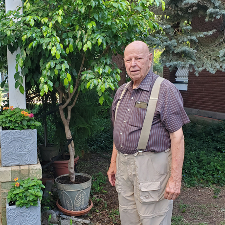 Man standing in backyard with tree to his right