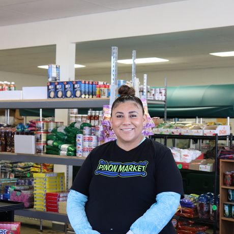 Woman with "Pinon Market" T-shirt, standing in grocery store