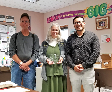 Three people holding a plaque