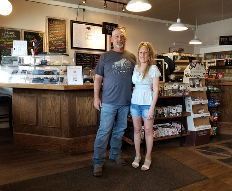 man and woman standing and smiling in front of counter in coffee shop