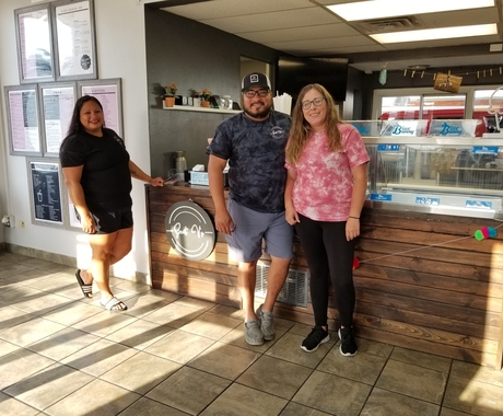 2 women and man standing in front of counter, posing