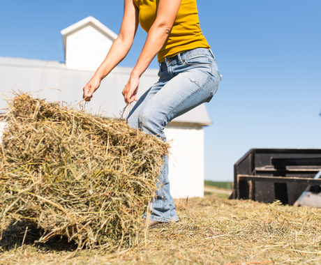 Female farmer lifting hay bale