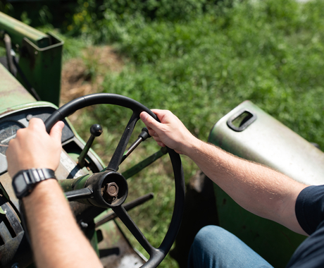 Hands on a tractor wheel, view is over the shoulder looking down