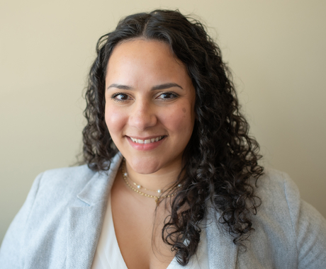 Woman with curly brown hair and gray jacket