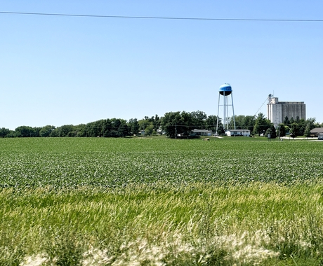 Rural landscape with water tower, homes, businesses and grain bin in the background.