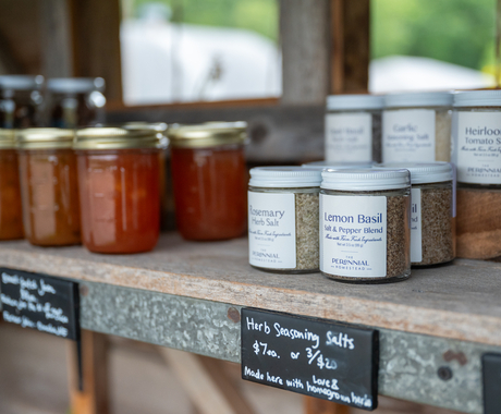 A shelf with glass jars of jam and glass jars of a spice blend