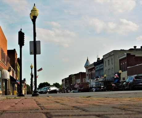 View of a rural Main Street from the street level with lamp posts on the right and buildings on both sides of the street.