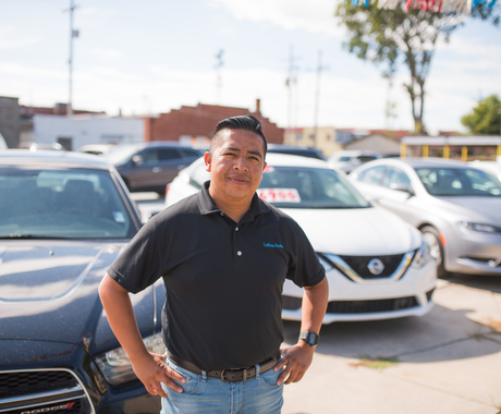 man posing in front of cars