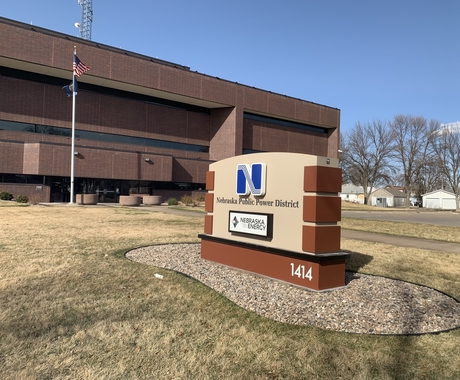 A sign reading Nebraska Public Power District with an office building in the background.
