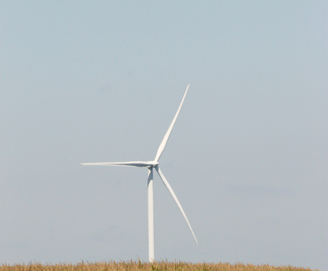 wind turbine in field with sky and clouds in background