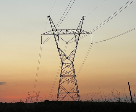 A power transformer stands in a field at sunset.