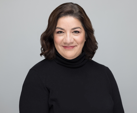 Hispanic woman with short dark brown hair wearing a black long sleeve turtle neck poses for a picture in front of a white background