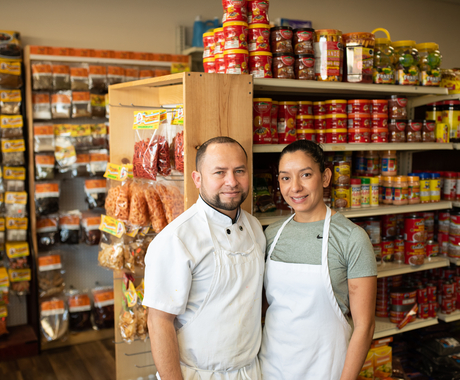 Man and woman wearing aprons standing in front of grocery store shelves