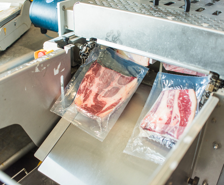 Wrapped packages of meat coming out of machine