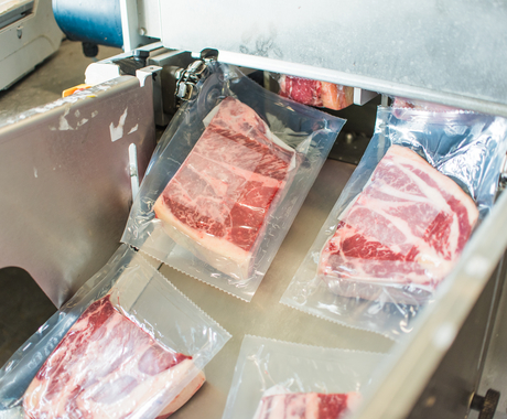 meat being sealed and rolling down conveyor belt