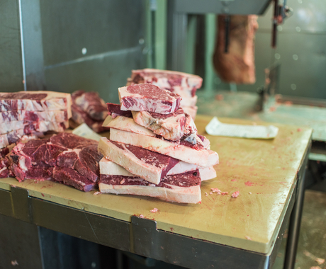 A pile of cut beef steaks on a butcher table