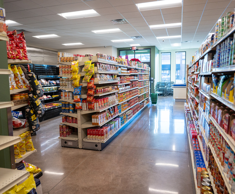 Aisles of food in a grocery store, containing bags of chips, cans of soup, and other institutional items