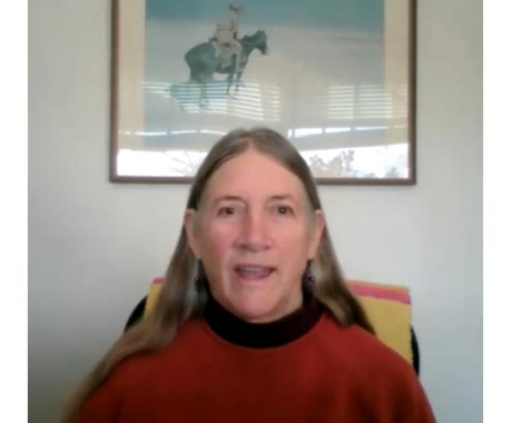 Margaret Scoles, executive director of the International Organic Inspectors Association, wears a red sweater and has long gray hair.