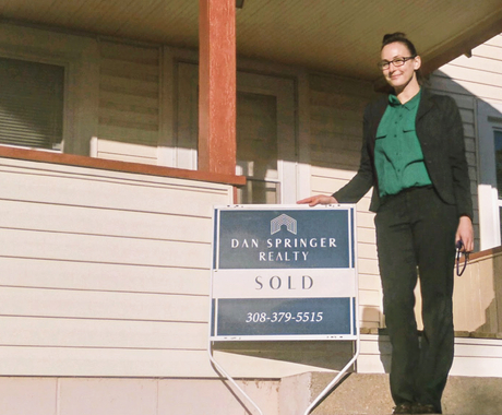 Alexandra Henry standing in front of a "sold" home sign