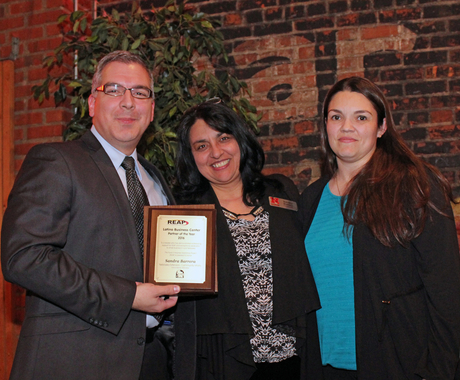 A man and two women with award
