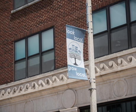 Light pole sign saying " look local. grow local." with brick and mortar building in background