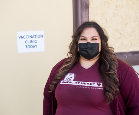 Woman wearing mask, standing in front of "Vaccination Clinic Today" sign