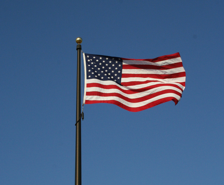 Bandera estadounidense vuela con el viento en un cielo azul oscuro sin nuves