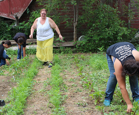 Family pulling weeds in front of barn