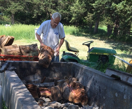 Man tossing wood into cattle cistern